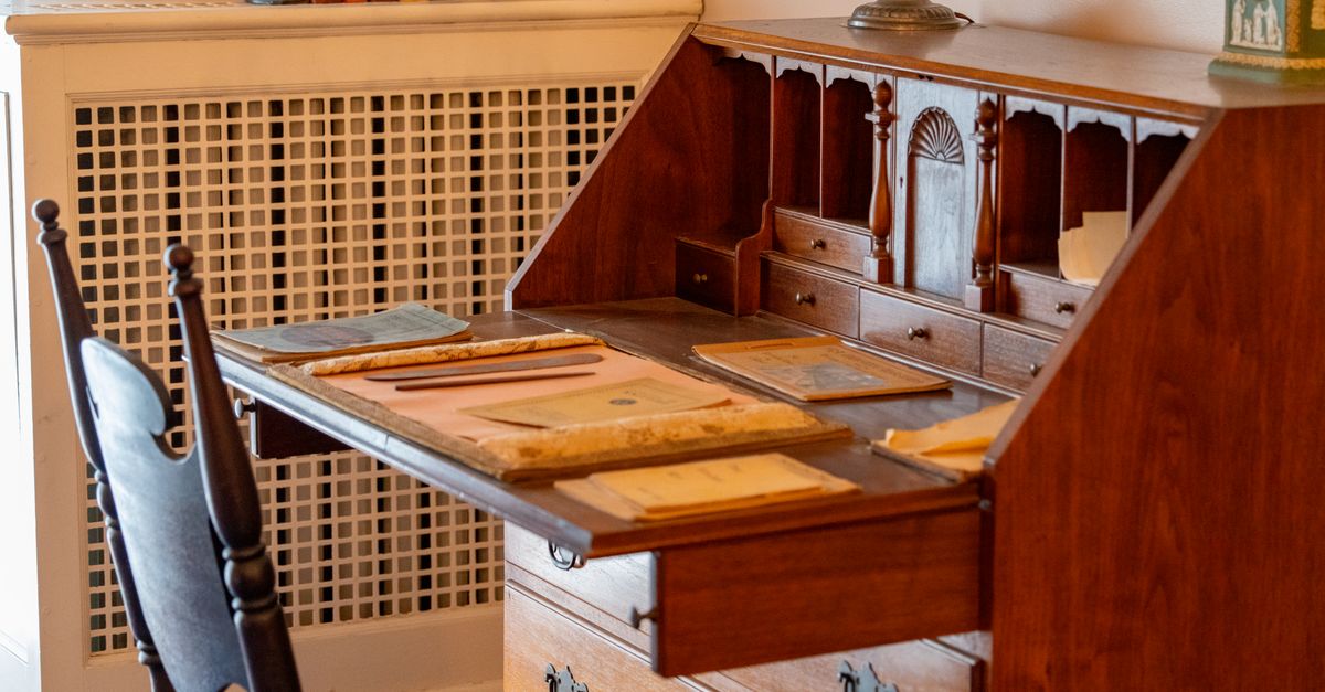 A charming wooden desk with vintage writing supplies in a cozy room.