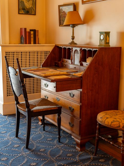 Free A classic wooden writing desk with books and decor in a cozy room setting. Stock Photo