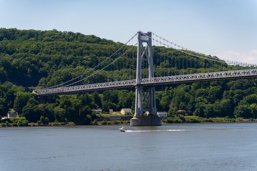 A serene daytime view of the Mid-Hudson Bridge spanning over the river with lush green forests in the background.