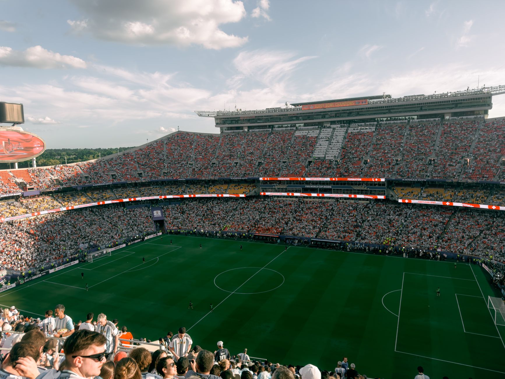 Aerial view of a lively soccer match in a bustling outdoor stadium filled with enthusiastic fans.