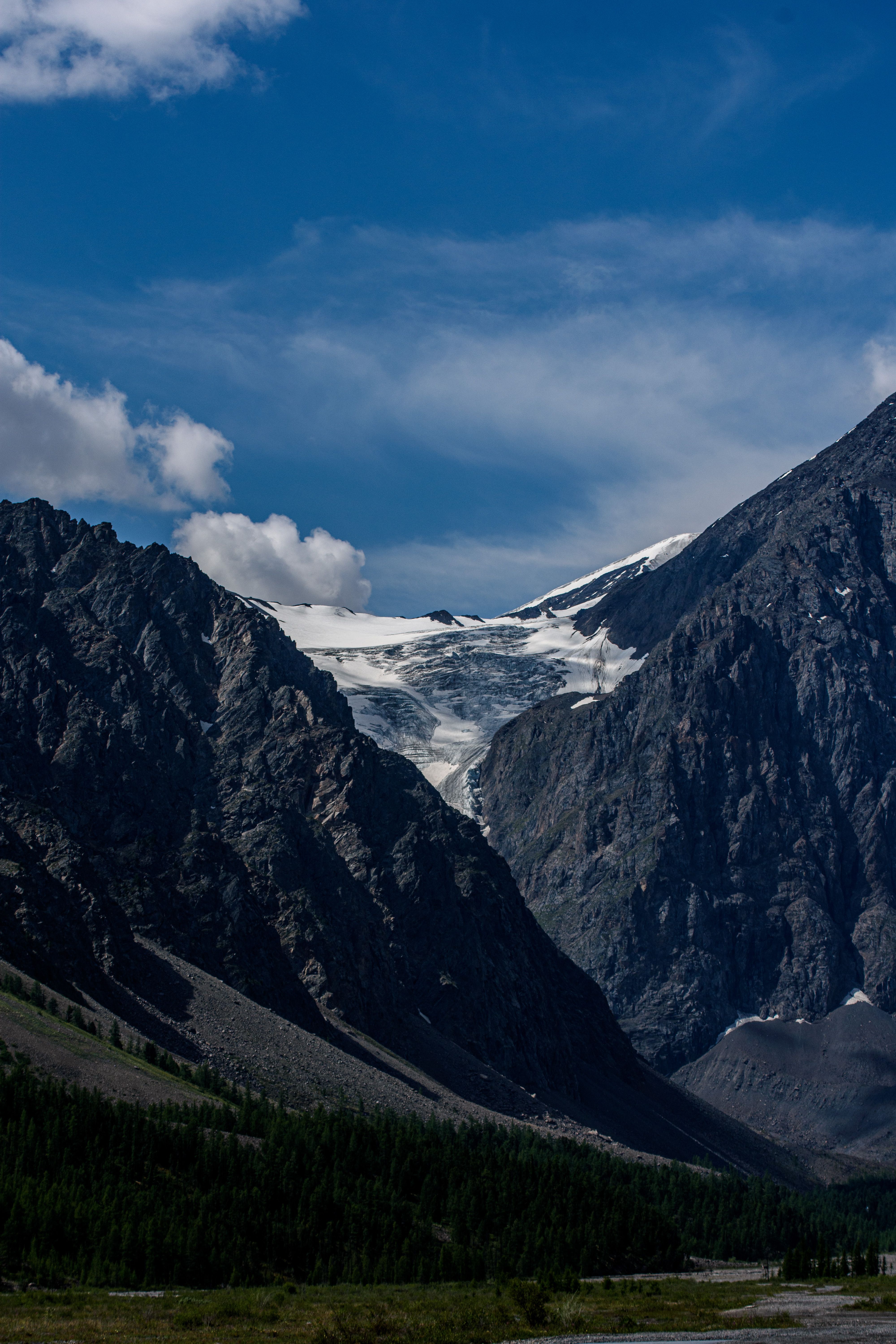 Stunning view of a glacier nestled in the rugged Altai Mountains under a vibrant blue sky.