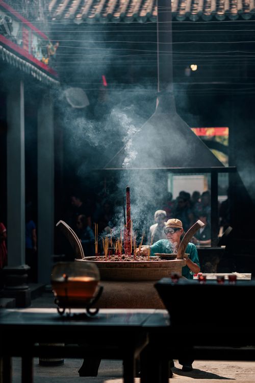 Free A serene moment of incense burning inside a traditional temple with soft light filtering through. Stock Photo