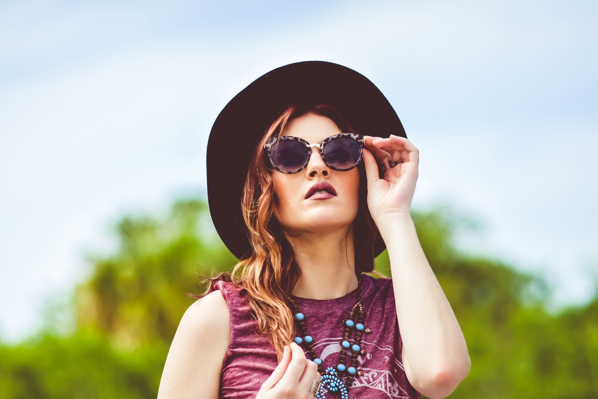Fashion-forward woman with hat and sunglasses in summer boho style