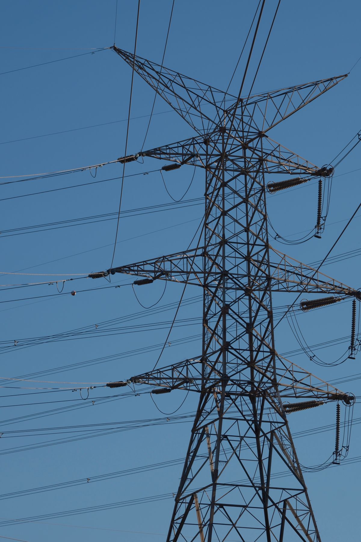 Electricity transmission tower with power lines under a clear blue sky, part of the system reviewed in a NERC compliance audit