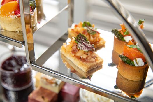 A close-up of an elegant afternoon tea tray featuring a selection of gourmet finger foods and desserts.