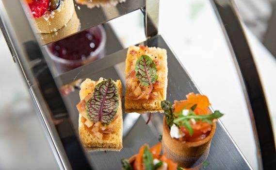 Delicious gourmet canapés beautifully arranged on a tiered stand, perfect for high tea.