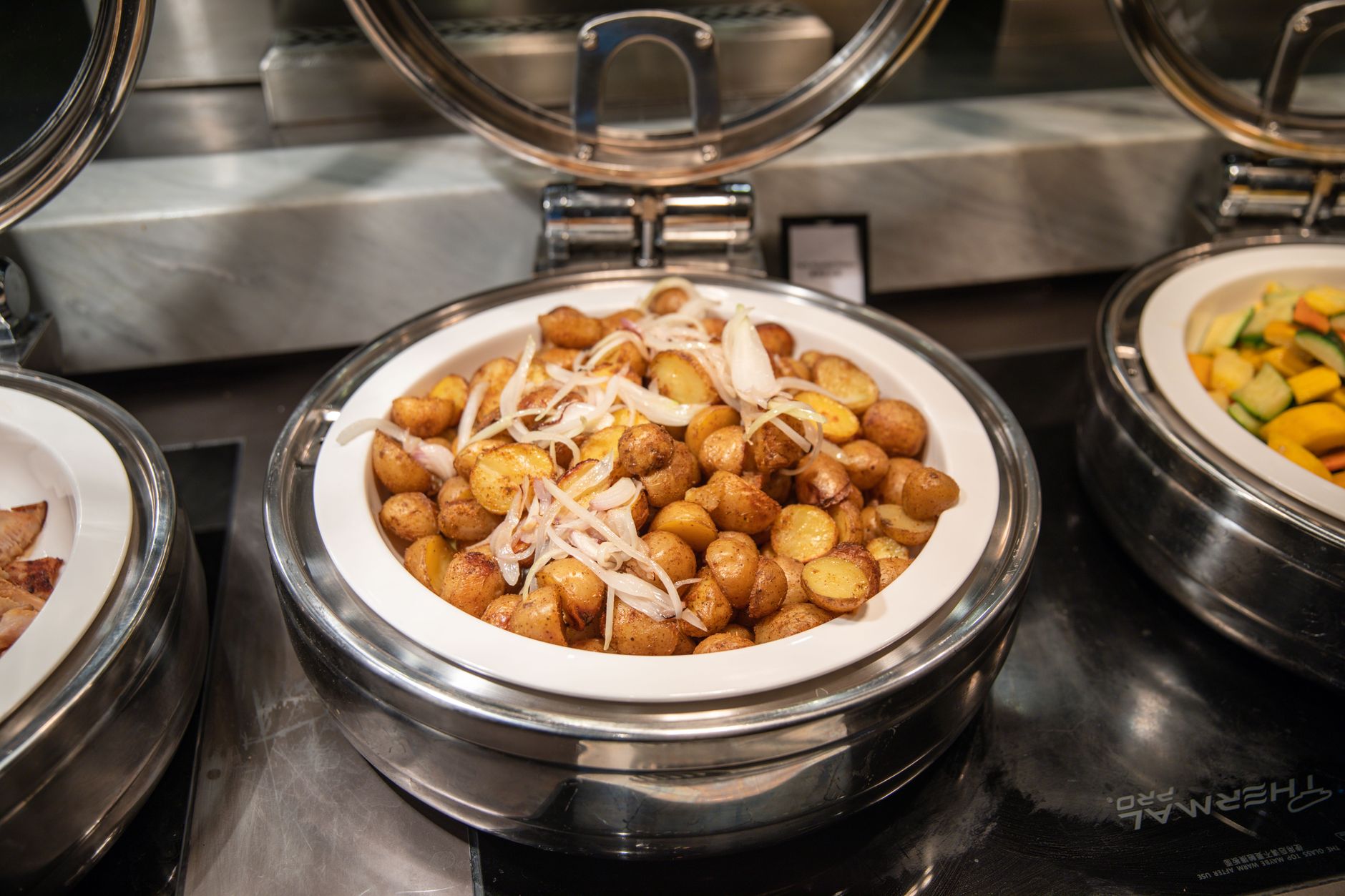 Delicious roasted potatoes with onions served in a buffet setting.