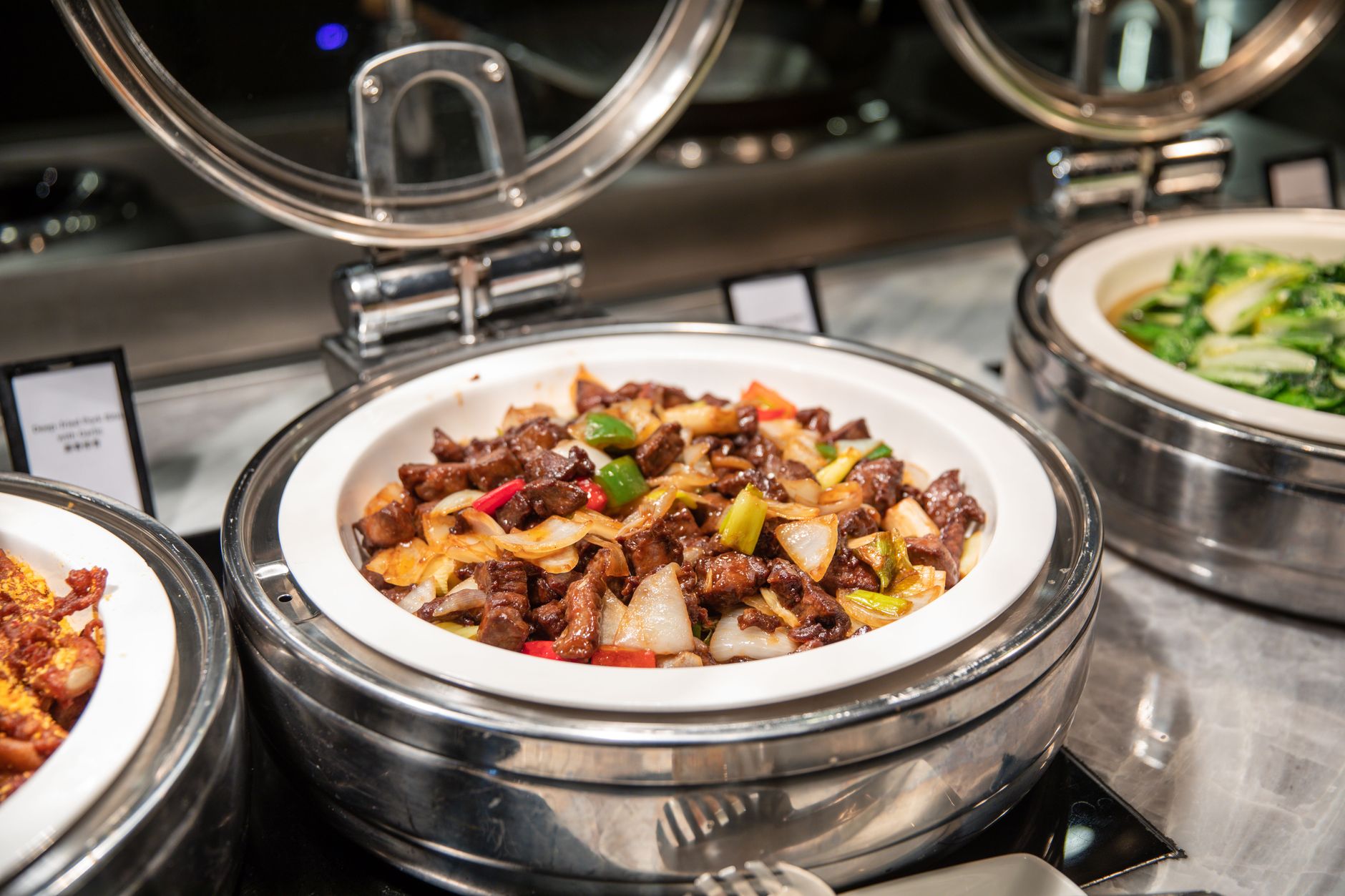 Close-up of buffet dishes featuring colorful Asian stir-fry with vegetables and other sides.