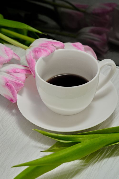 Free A delicate arrangement of pink tulips and a cup of coffee, perfect for a serene morning. Stock Photo