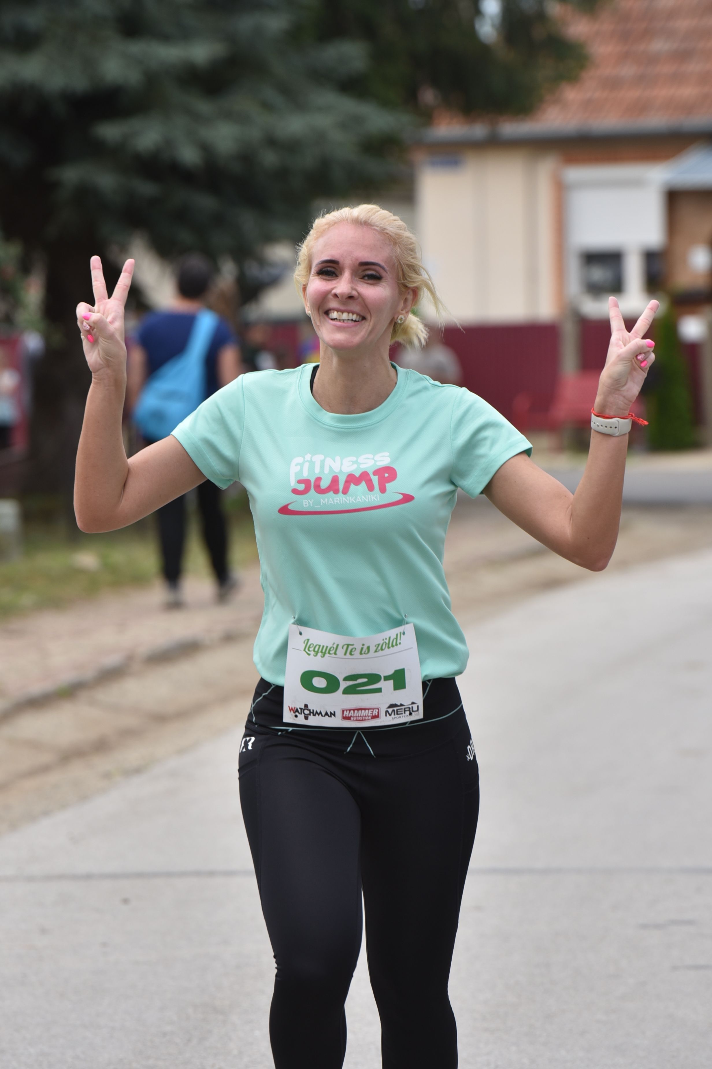 Smiling female runner making victory signs during a road race.