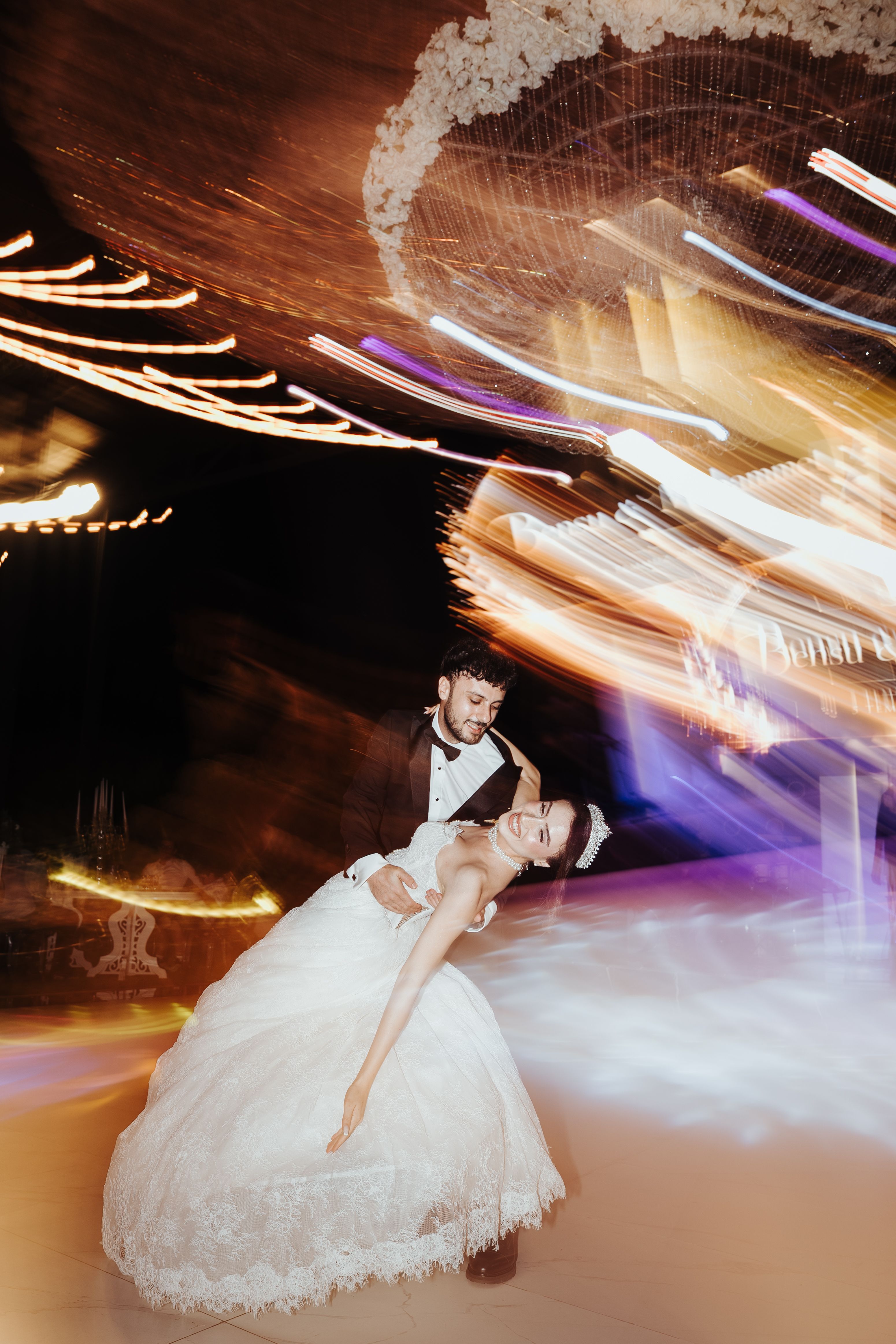 Bride and groom share a romantic dance under vibrant lights at an outdoor wedding in Antalya, Türkiye.