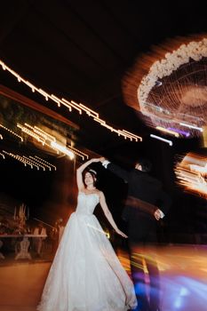 A couple elegantly dances under twinkling lights at an outdoor wedding ceremony in Antalya.