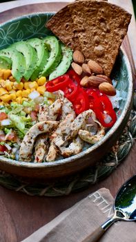 Delicious chicken salad bowl with avocado, corn, and nuts.