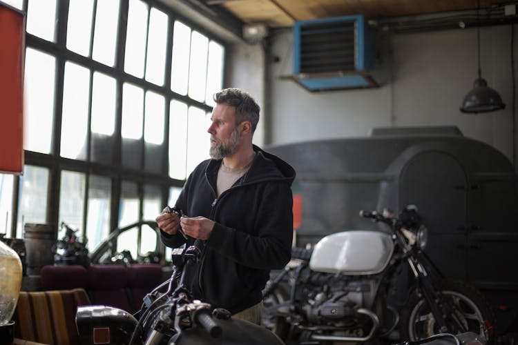 Gray Haired Mechanic Renovating Motorcycle In Garage