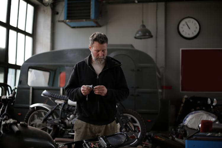 Serious Bearded Man Working With Motorcycle In Garage