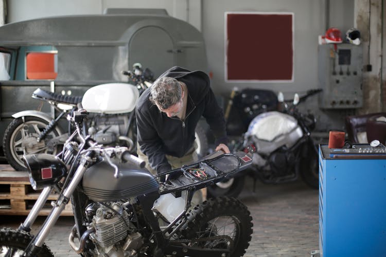 Anonymous Adult Male Mechanic Fixing Motorbike In Garage