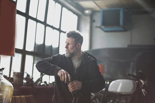 Confident bearded male mechanic working in modern garage