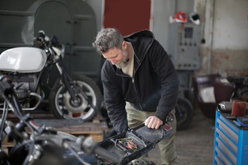 Serious adult male mechanic repairing motorbike in garage