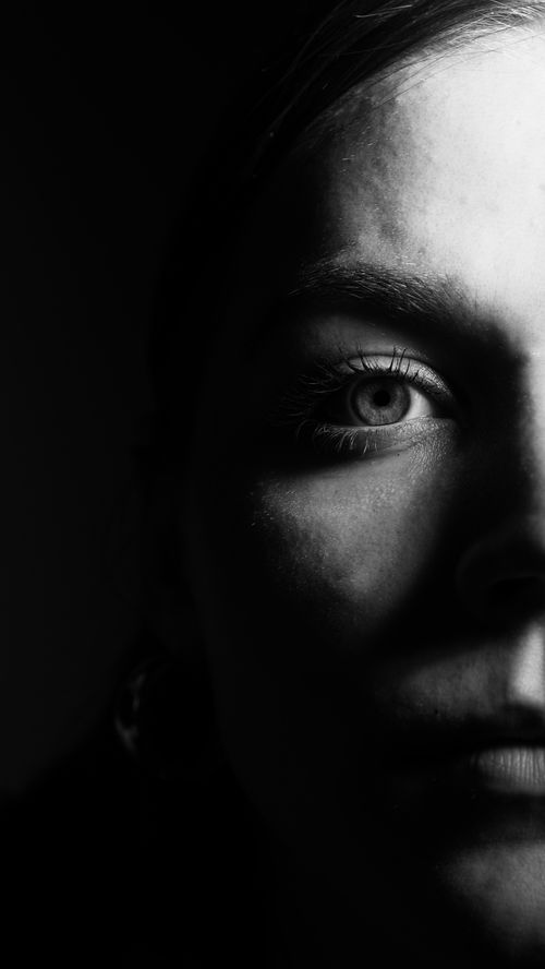 Free Moody black and white portrait of a woman with dramatic lighting highlighting half her face. Stock Photo
