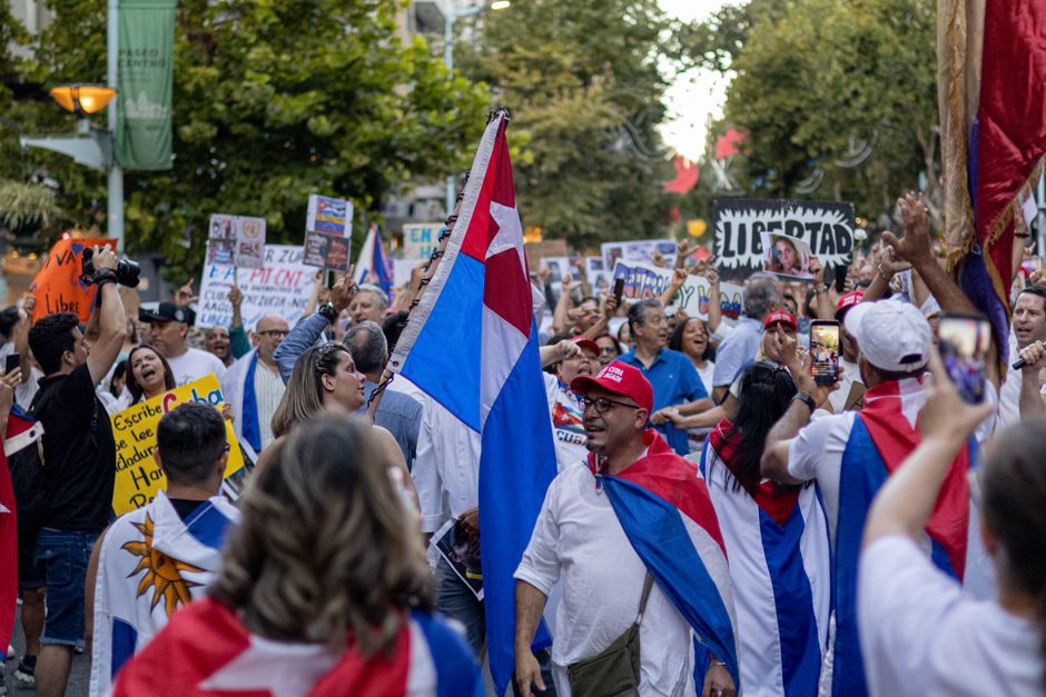 Colorido desfile por la calle con banderas cubanas y una multitud jubilosa celebrando la independencia.