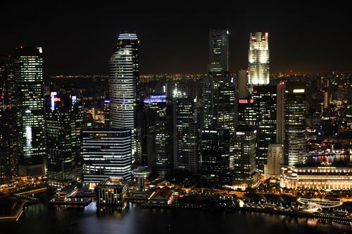 Free A breathtaking view of a city skyline at night with illuminated skyscrapers reflecting on the river. Stock Photo
