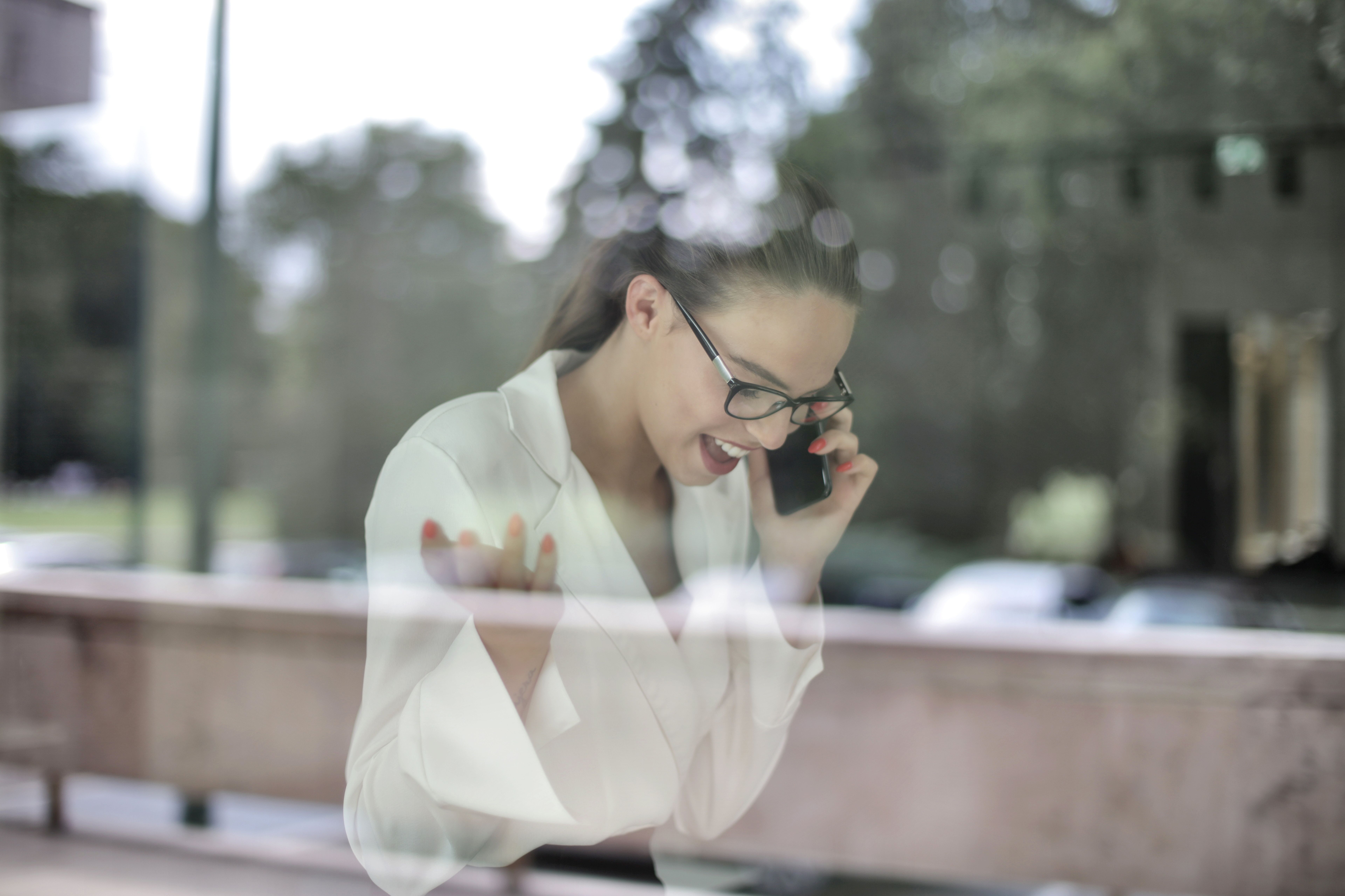 女商人戴着眼镜打电话，透过窗户向外看