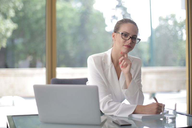 Confident woman in glasses working at a desk, embodying modern professionalism.