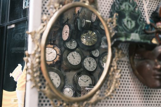 A collection of vintage clocks reflected in an ornate antique mirror in Bengaluru, India.