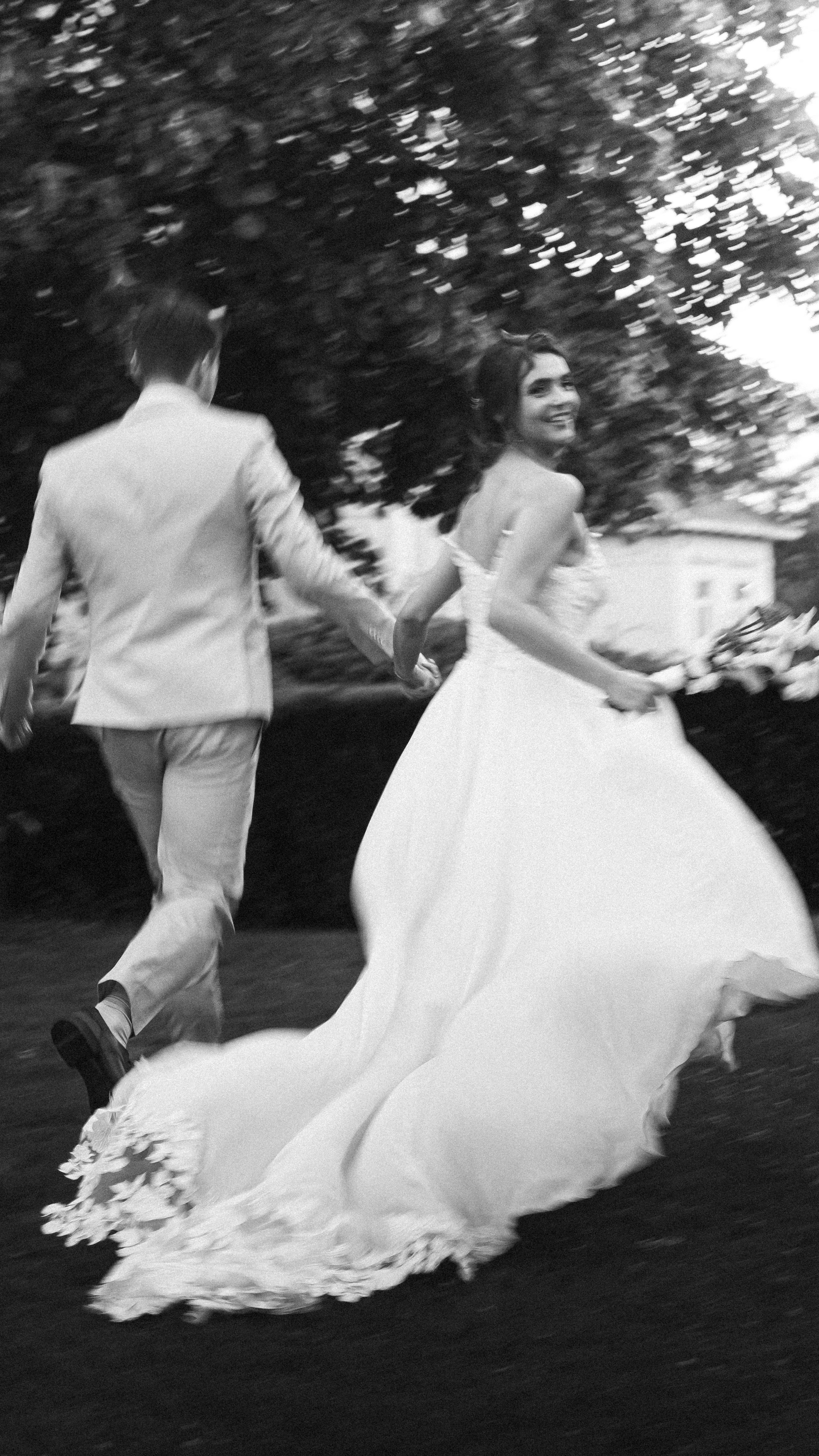 Artistic black and white image of a joyful newlywed couple running outdoors in Hamburg.