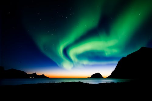 Silhouette of Mountains under Aurora Borealis and Starry Sky