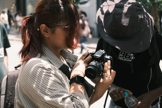 Woman examining a camera on a busy street in Bengaluru, India.
