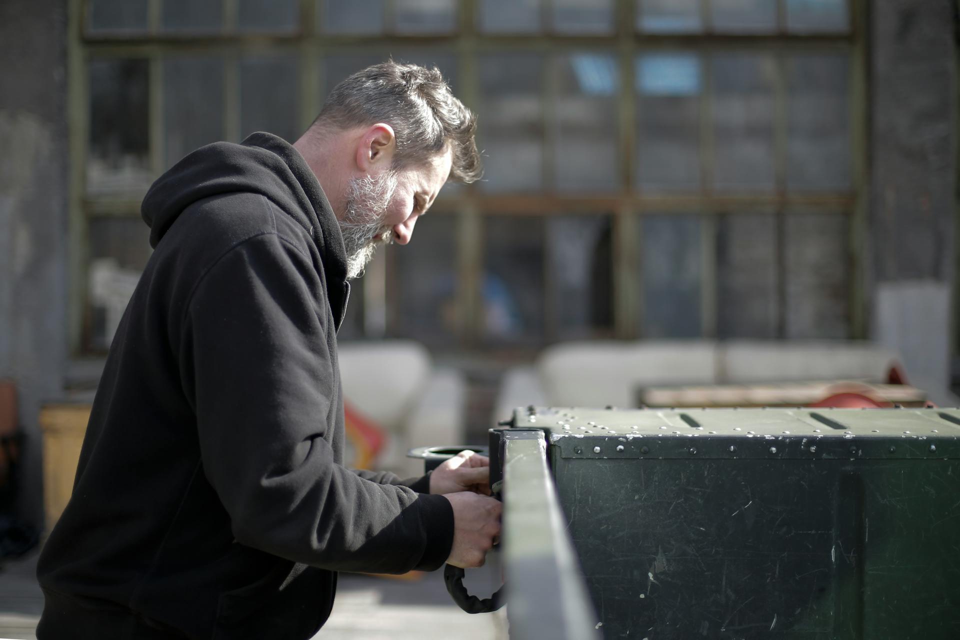 Professional mechanic concentrating on vehicle inspection in a garage. Demonstrates technical expertise and attention to detail.