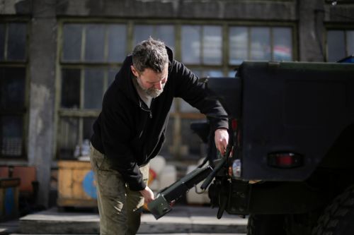 Free Side view of serious adult bearded mechanic in workwear standing near car on street near garage and repairing metal door of trunk Stock Photo