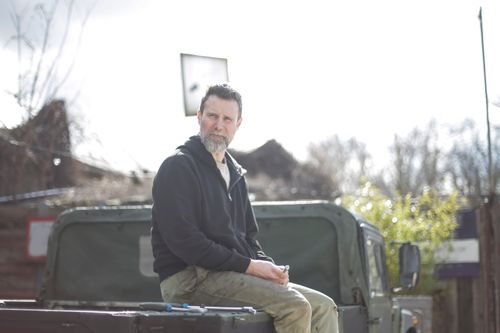 Free A middle aged man with facial hair sitting on a vehicle outdoors in a park during fall. Stock Photo