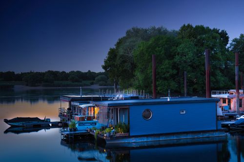 Free Peaceful houseboats on a serene river at twilight in a lush green setting. Stock Photo