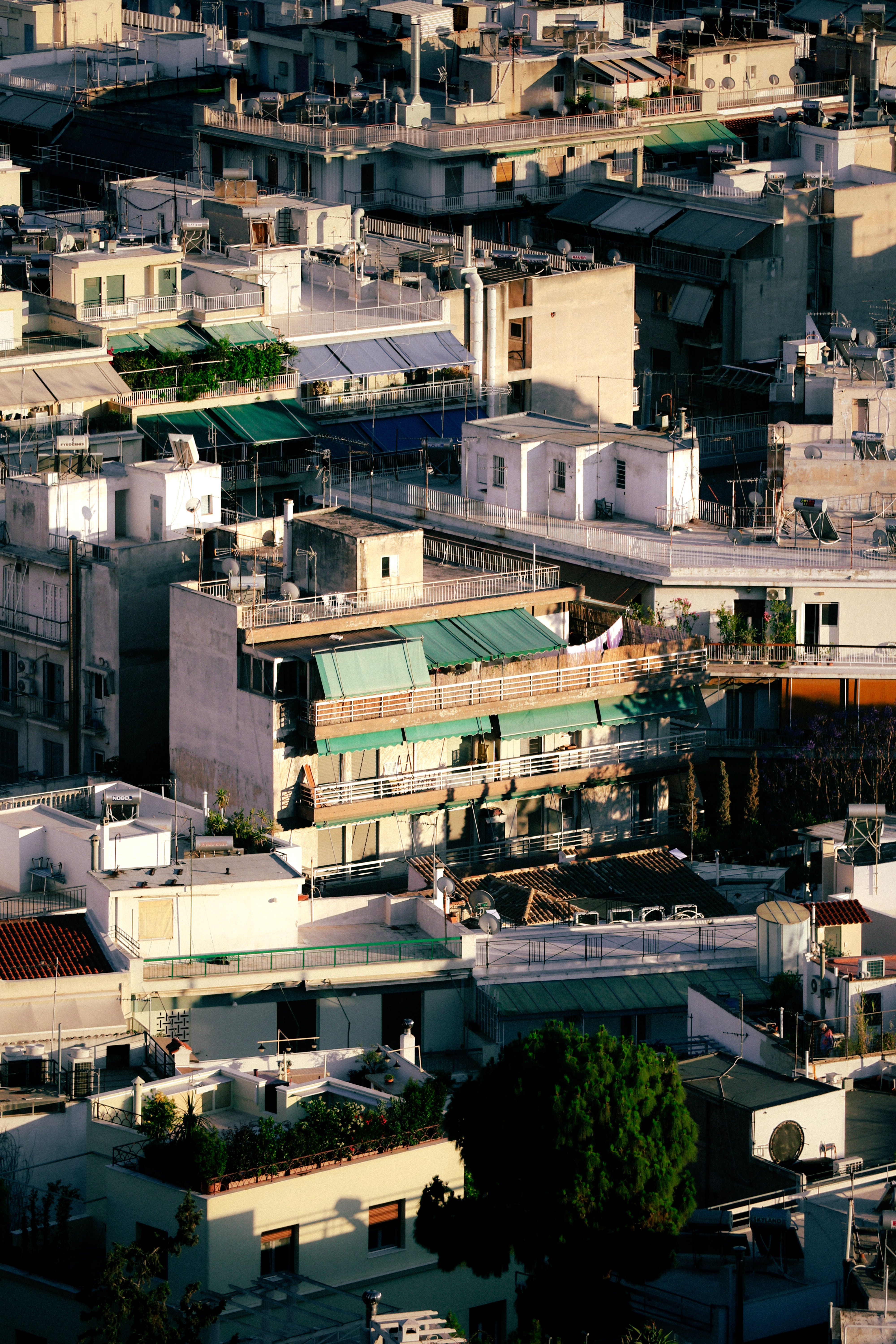 An aerial perspective showcasing densely packed buildings in Athens, Greece during sunset, highlighting urban architecture.