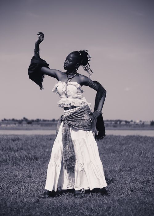 Free Elegant portrait of a woman dancing outdoors on a grassy field in monochrome, exuding grace and freedom. Stock Photo