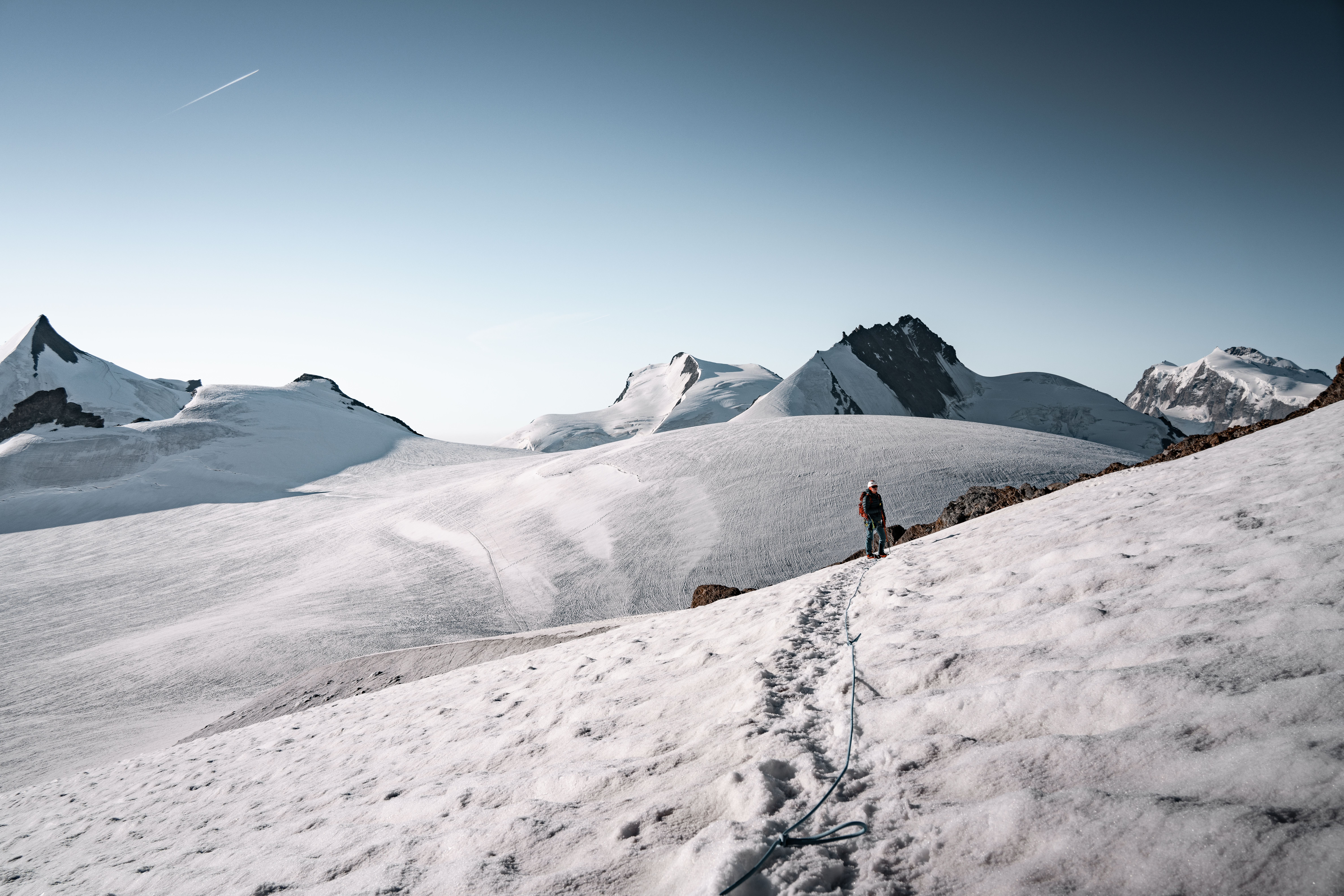 A lone hiker climbs the snowy peaks of Zermatt in the Swiss Alps, under clear blue skies.. Photo by Tobi &Chris on Pexels