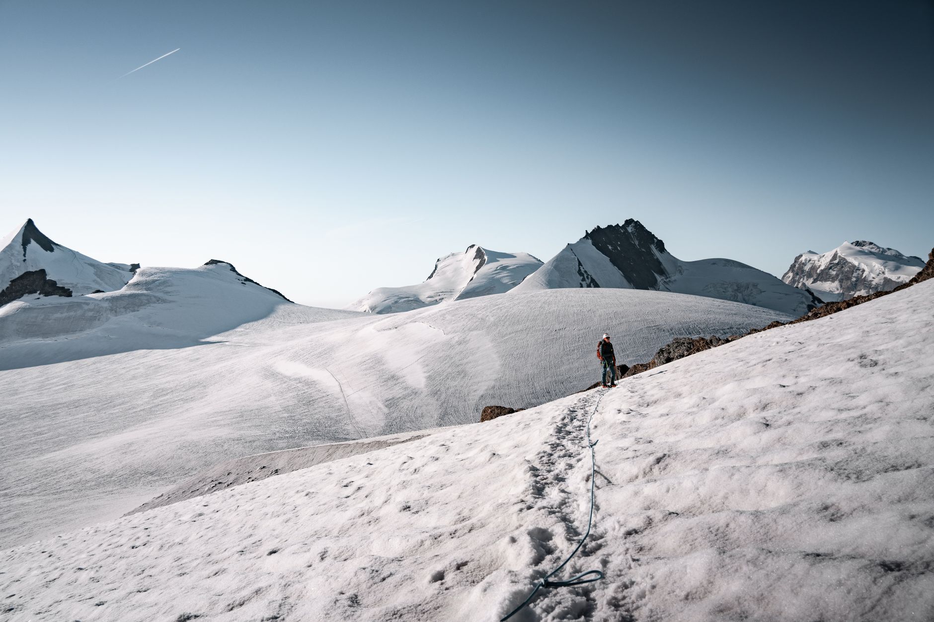 A lone hiker climbs the snowy peaks of Zermatt in the Swiss Alps, under clear blue skies.. Photo by Tobi &Chris on Pexels