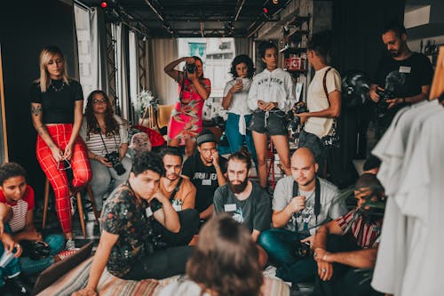 Free Group of multiracial people wearing casual outfits gathering together in modern studio near female speaker on mat and listening attentively Stock Photo