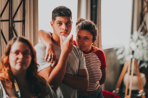 Free Three friends casually posed in a warmly lit indoor setting, creating a relaxed and intimate atmosphere. Stock Photo