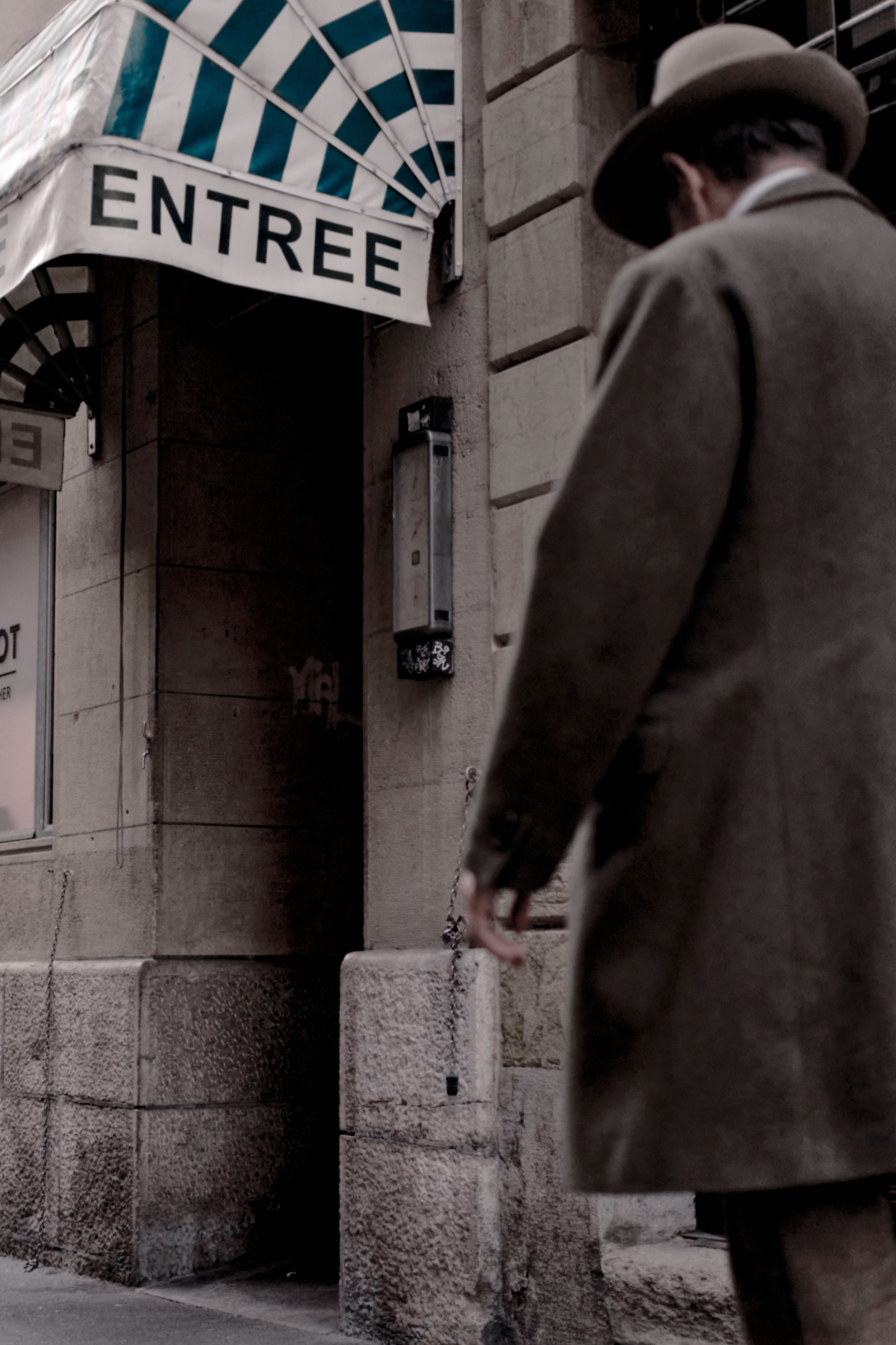 Classic street scene in Neuchâtel, Switzerland featuring a vintage sign and man in coat.