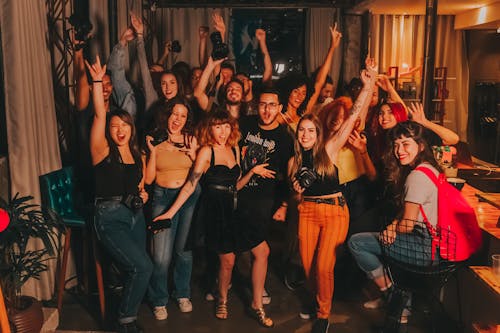 Free High angle of excited young diverse friends in casual outfits with arms raised yelling happily while celebrating project success in modern workspace Stock Photo