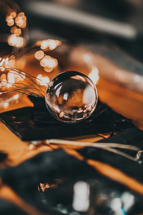 High angle of transparent glass ball placed on gift sack and reflecting lights of glowing garland