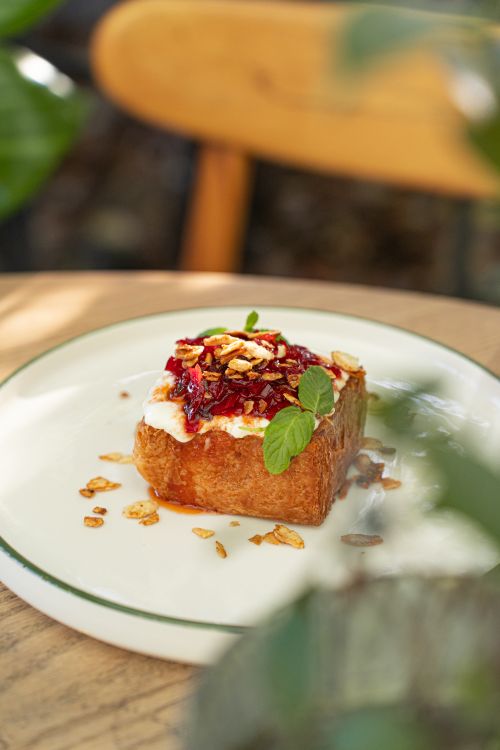 Free Savor this gourmet slice of toast topped with cream and vibrant fruit in a rustic outdoor setting. Stock Photo