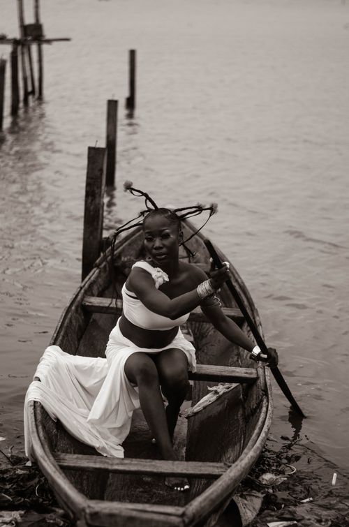 Free A woman in traditional attire navigates a canoe on a serene waterway in Oworonshoki, Nigeria. Stock Photo
