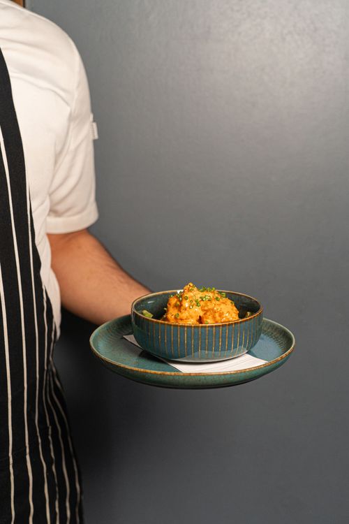 Free Close-up of a gourmet dish in a blue bowl presented by a waiter indoors. Stock Photo
