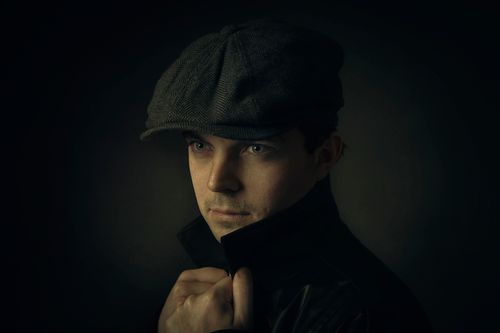 Free Moody portrait of a man wearing a cap in a dark setting, showcasing intense expression. Stock Photo