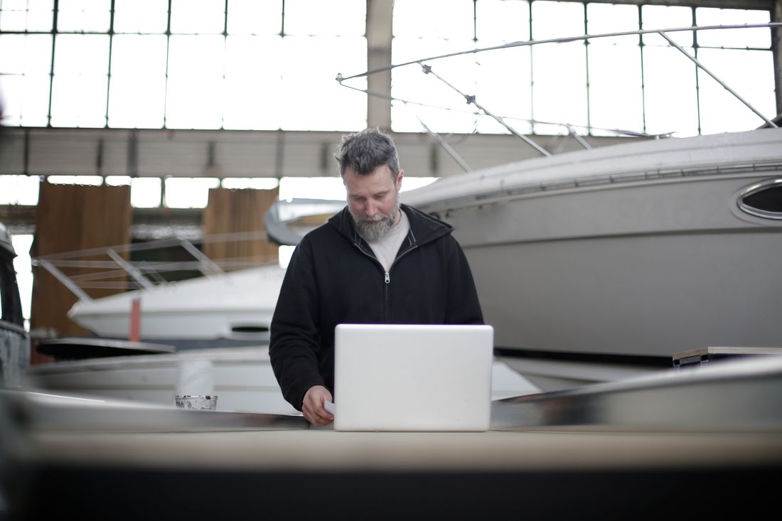 A business owner working on a laptop inside a boat hangar