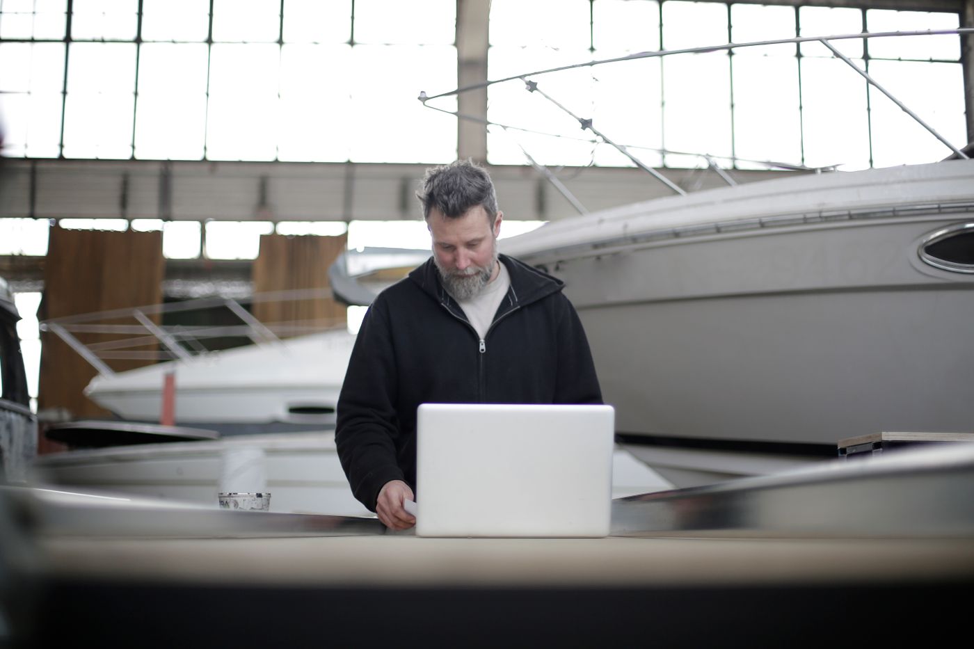 An owner working on a laptop in a boat hangar
